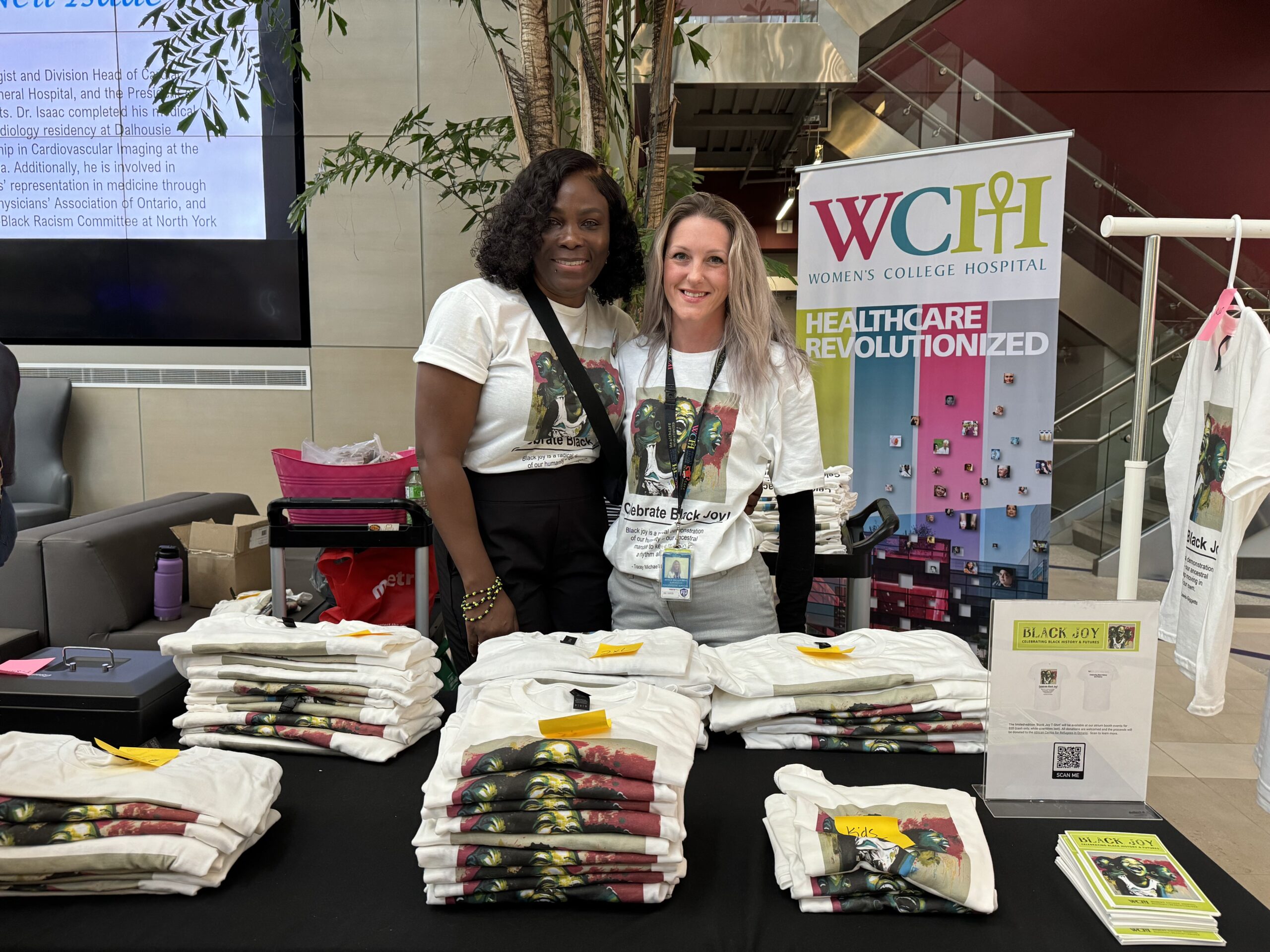Two employees at Women's College Hospital giving out t-shirts for Black History and Futures Month