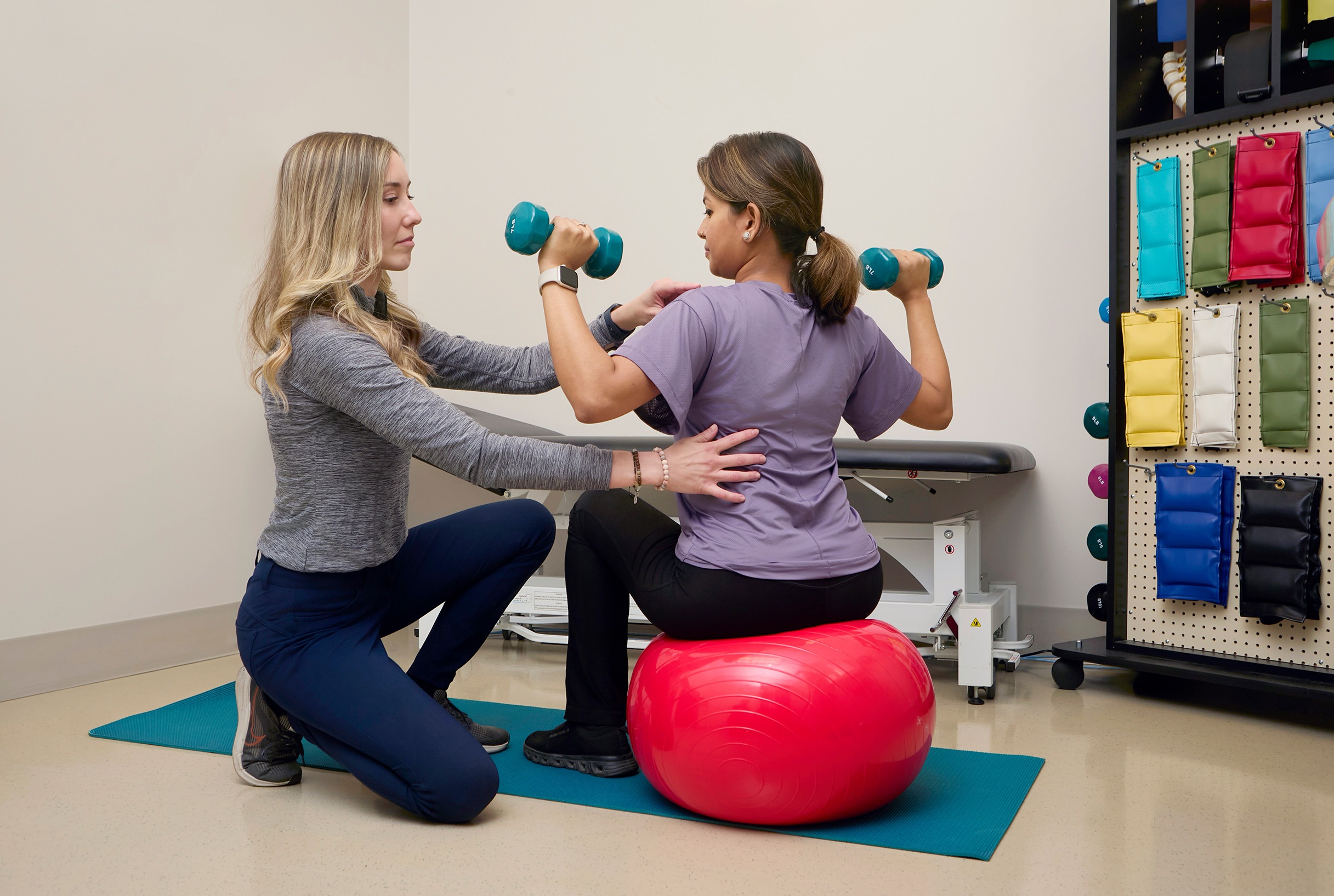 Olivia Drodge working with patient doing exercise with medicine ball and dumbbells 
